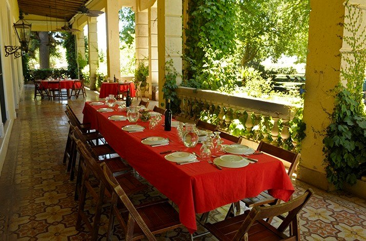 Tables are beautifully arranged for a dinner party with the red tableware at the outdoor area of Areco Tradicion - San Antonio de Areco.