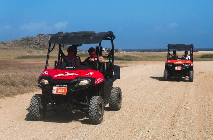 Two ATVs carrying people on a drive around iconic landmarks in Aruba.