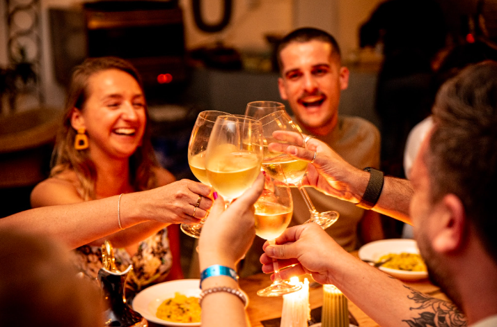 Friends clinking glasses of white wine in a celebratory toast over dinner.