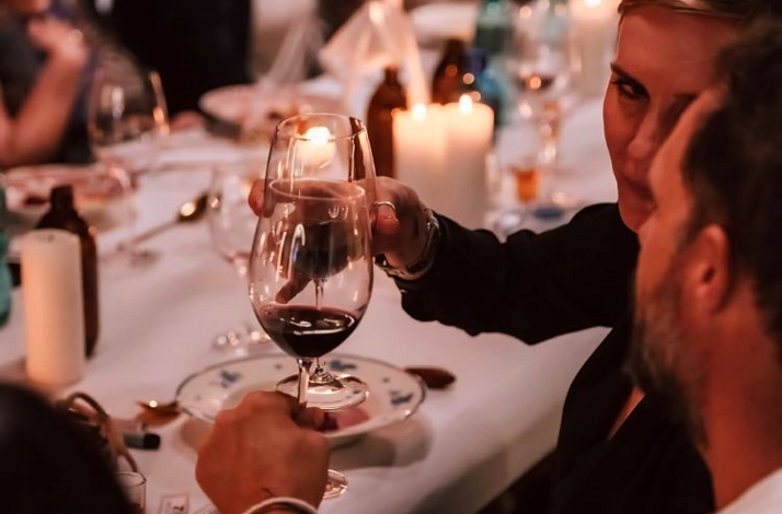 Close-up of two guests clinking wine glasses in a toast during an intimate, candlelit dinner.