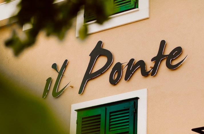 The  il Ponte logo on the wall of the restaurant captured from behind bushes.