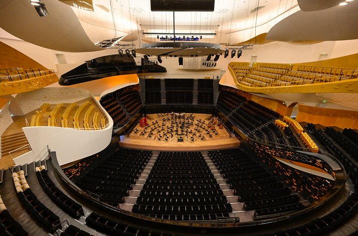 Futuristic concert hall of Philharmonie de Paris with curved balconies and seating surrounding a central orchestra stage.