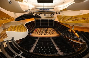 Futuristic concert hall of Philharmonie de Paris with curved balconies and seating surrounding a central orchestra stage.