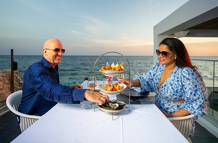 A couple having dinner at Saint Tropez Ocean Club in Willemstad with the sea on the background.