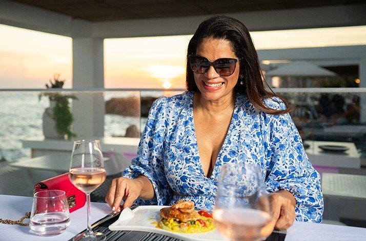 A young woman about to have dinner served from special menu with pink wine at luxurious Saint Tropez Ocean Club in Willemstad.