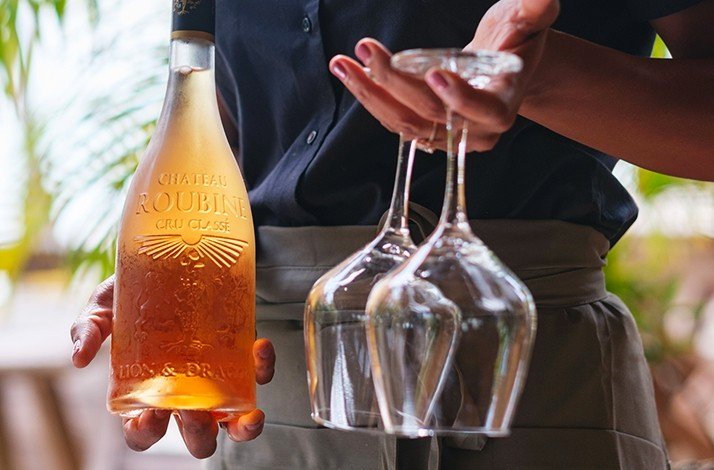 The waiter serving 2 glasses with an orange drink.