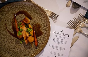 SecretEATS menu next to a dish prepared for an exclusive mystery dinner at a surprise venue in Johannesburg.
