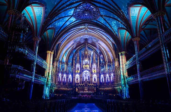 The gothic style interior lit with dim blue lights of Notre-Dame Montreal