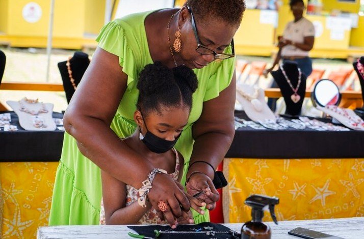 A girl crafting a Junkanoo-themed wristband as a souvenir.