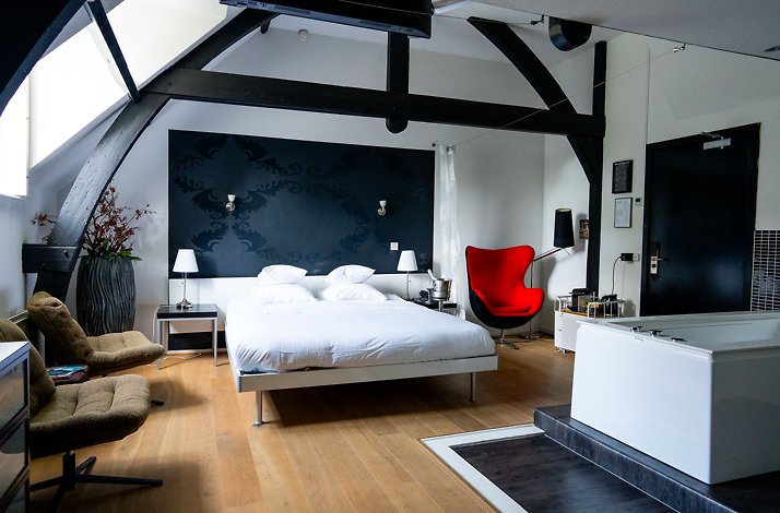  Hotel Ville Ruimzicht modern room with double bed, red chair, and in-room bathtub.
