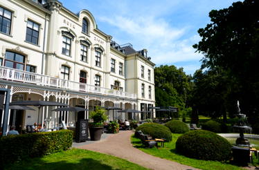 Elegant Hotel Villa Ruimzicht exterior with garden, fountain, and terrace seating.