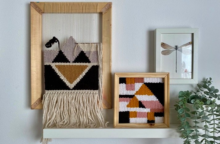 A loom with a half-finished creation process, on a wall with different frames, weaving creations and a painting of a dragonfly