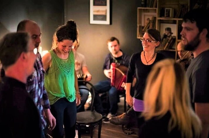 A group of people laughing during Irish dance lesson