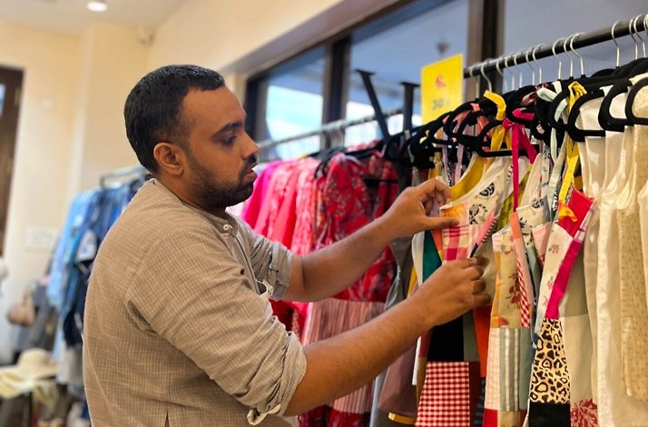 Man looking through clothes on a rack in one of the clothing stores in Panjim, India.