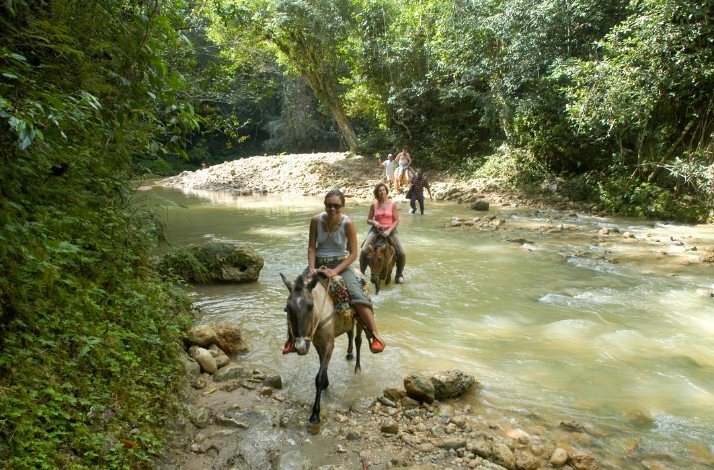 A group of people crossing river on horses in Samaná, Dominican Republic.