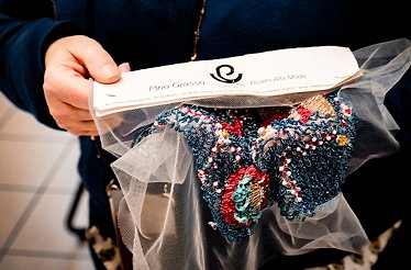 A close-up of hands holding an embroidery piece created at the Pino Grasso Ricami atelier in Milan.