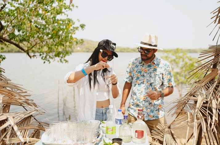 Young man and woman in summer clothes mixing cocktails at Sai Island in Goa, India.