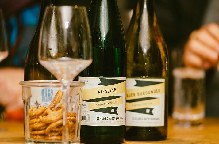 Two bottles of wine put beside a glass for wine on a table