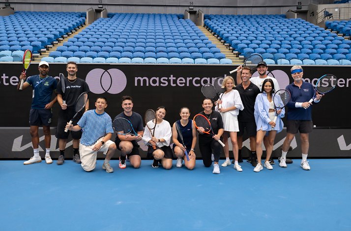 A group of tennis players posing for a group photo holding rackets on a blue tennis court.