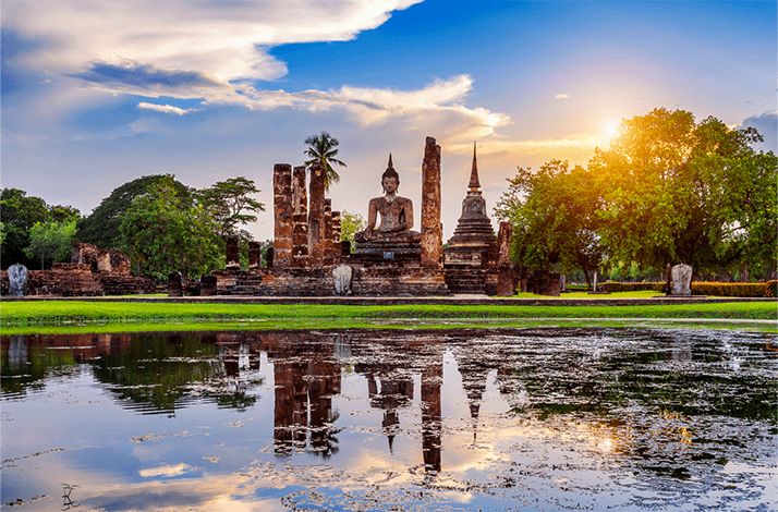 Sunset over a pond and Buddha statue in Ayutthaya, Thailand.