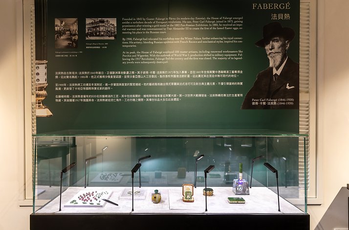 Museum exhibit featuring a portrait of Peter Carl Fabergé above a glass case containing intricate enamel and gemstone artifacts.