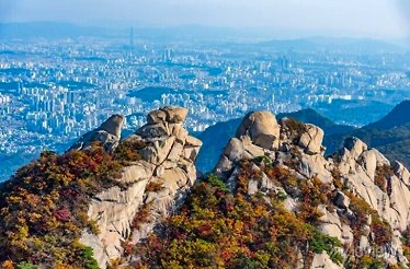 Scenic view over the high rocks overlooking urban view in distance from Bukhansan National Park, South Korea.
