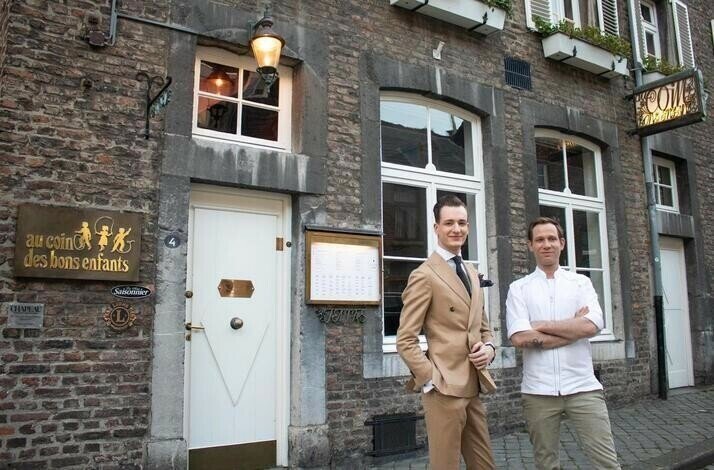 Two men in suits standing in front of Au Coin des Bons Enfants.