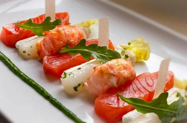 Sliced white and red fish and shrimps on the plate.