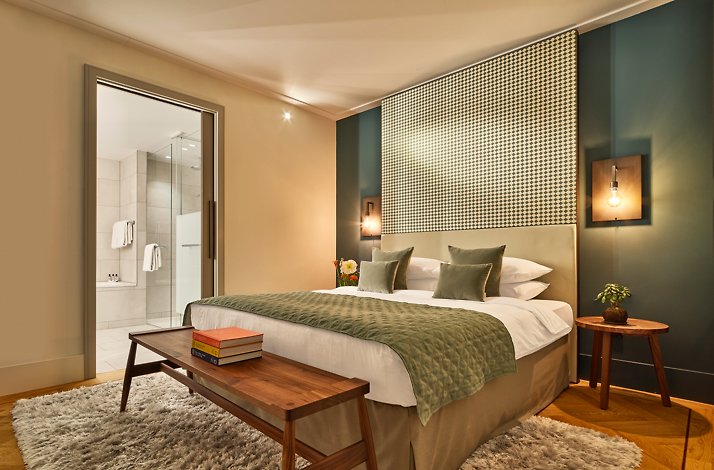 A modern guest room with green walls and a plush king bed at the Hyatt Regency Amsterdam hotel.