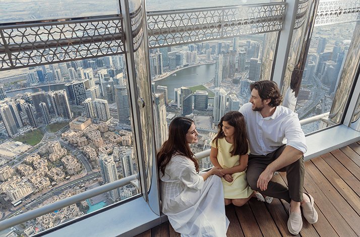 Happy family enjoying the city view through panoramic windows At the Top, Burj Khalifa.