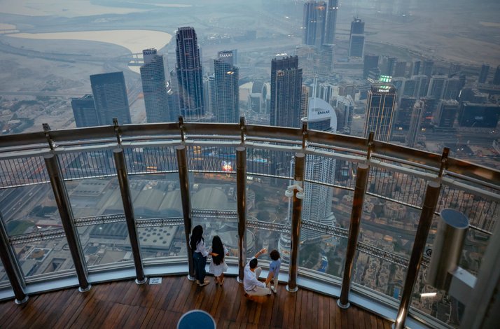 Parents with son and daughter view Dubai buildings from At the Top, Burj Khalifa.