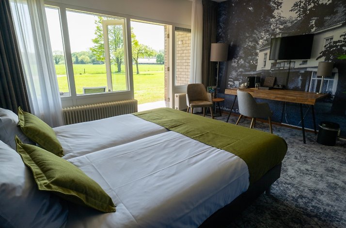 Cozy luxury hotel room overlooking green estate.