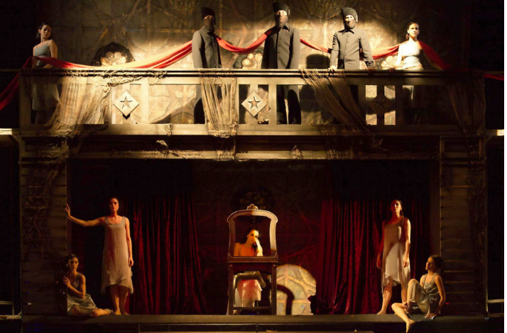 Ballet dancers performing on a theatrical stage with balcony scenery