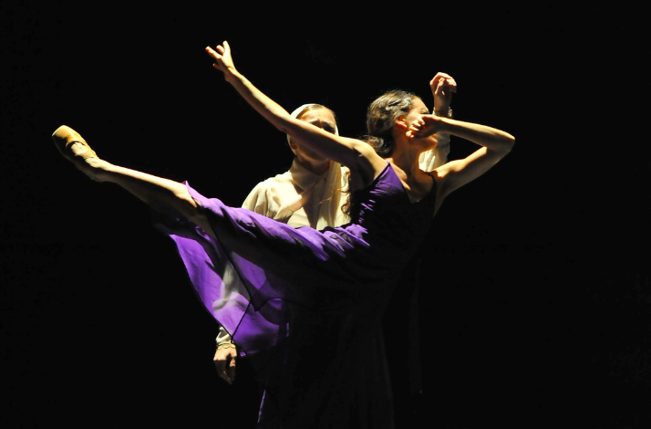 Two ballet dancers performing a dramatic lift on stage.