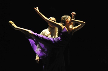 Two ballet dancers performing a dramatic lift on stage.