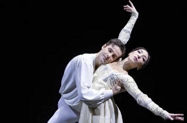 Two dancers portraying Romeo and Juliet against a black background