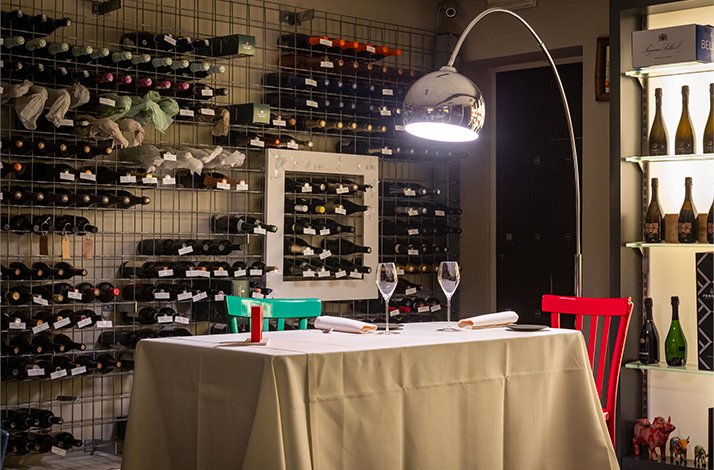 Minimalist dining setting at Ristorante Trequarti, featuring colorful chairs, wine glasses, and an extensive wine wall display.