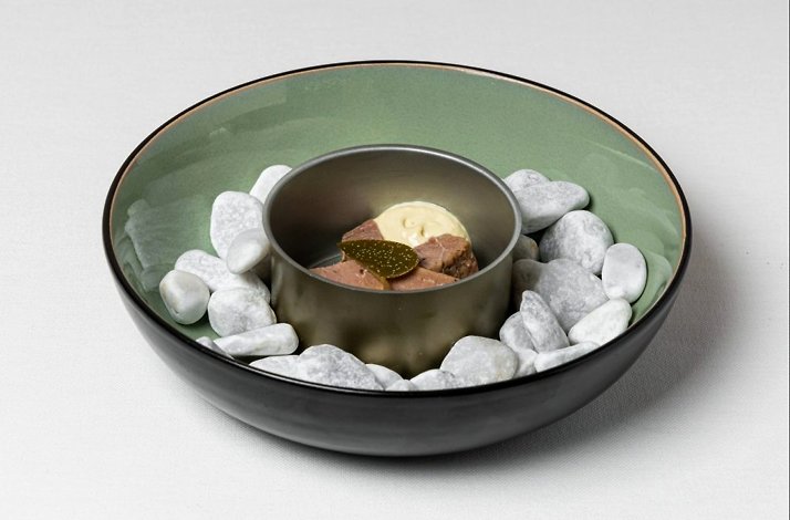 A bowl of ice cream and chocolate served in a plate surrounded by stones at Atelier Restaurant e Bistrot