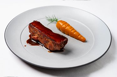 Glazed meat cut with rich dark sauce and a whole glazed carrot topped with dill, plated minimalist-style at Ristorante Trequarti.