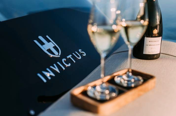 Two glasses filled with wine and Invictus logo on the table.
