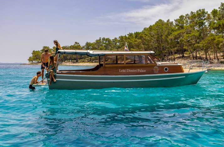 A yacht in the water with trees on the background.