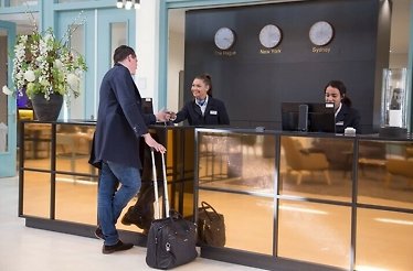 A man checks in at the New Mondrian Hotel and the receptionist smiles at him.