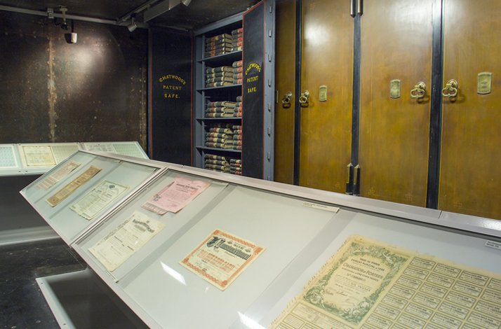 Display cases with old bank documents, certificates, and a vault door at the Ottoman Bank Museum.
