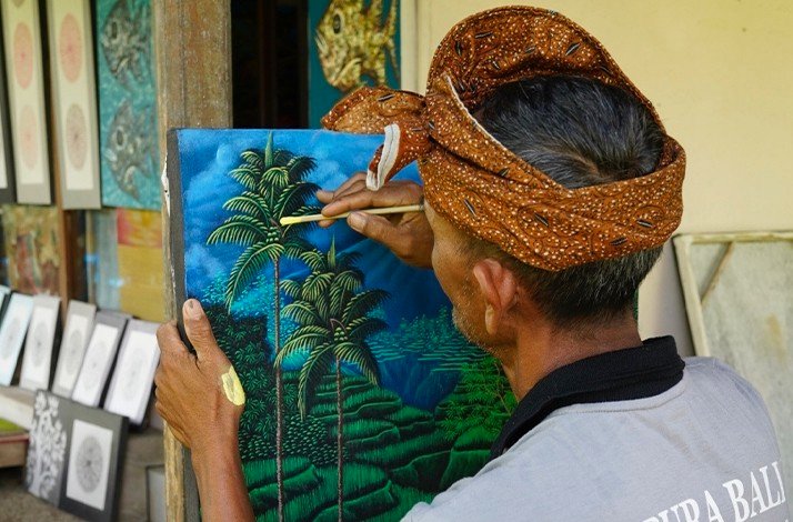 Balinese artist painting a coconut tree.