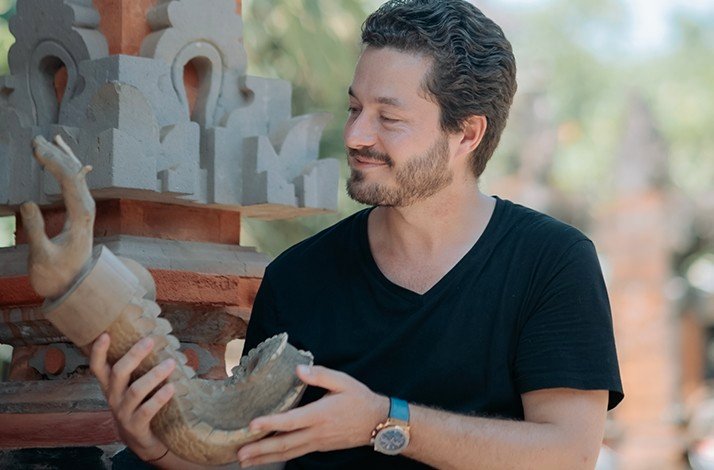 Man holding a wood carved art made by a balinese artist.