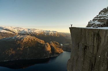 A picturesque view on fjord and a man standing with raised hands.
