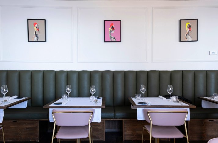 Dinning area at Villa Pizzini decorated with pink and green seats and colorful painting on the wall