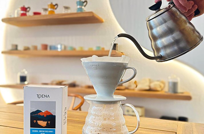 A person pouring water into the cup from a teapot.
