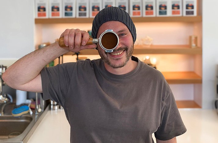 A smiling person holding a filter holder next to their eye.