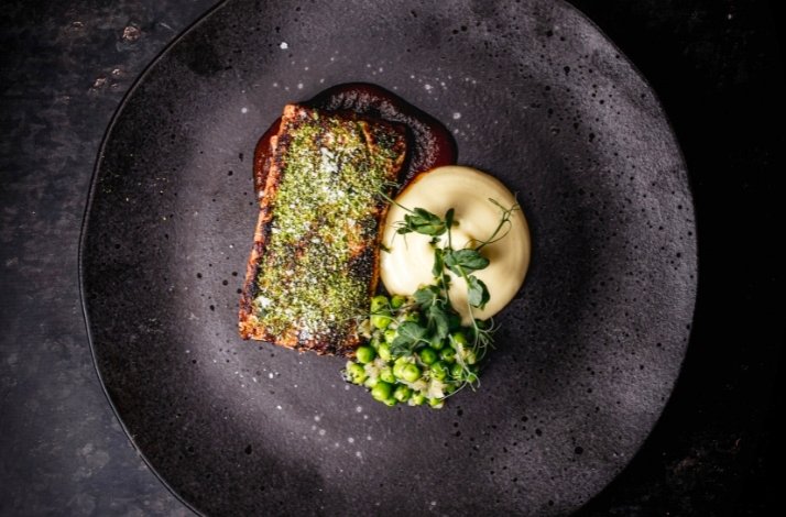 View from the top of a gourmet meal served on a black plate.